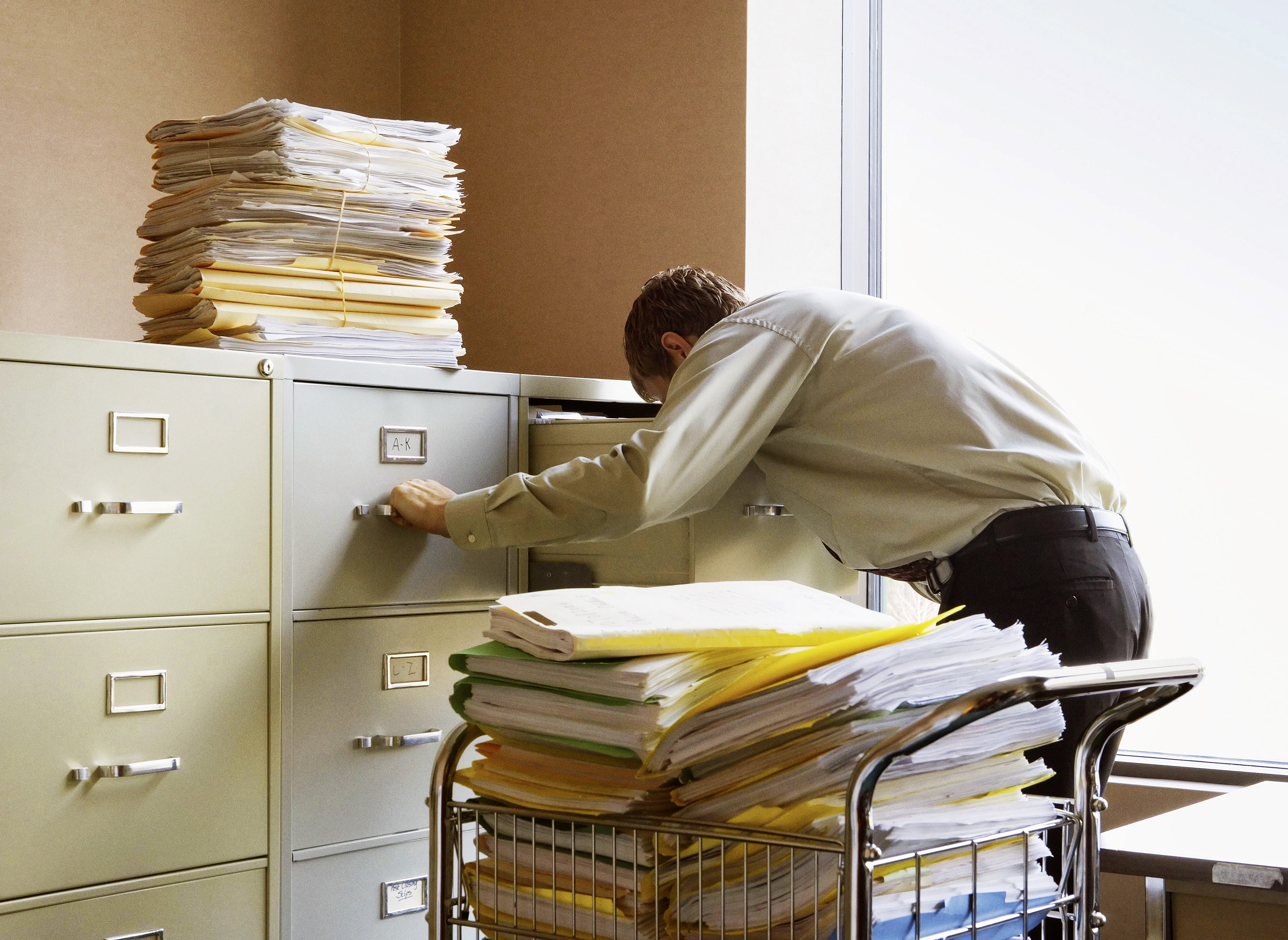 Businessman searching for documents in metal file cabinets.