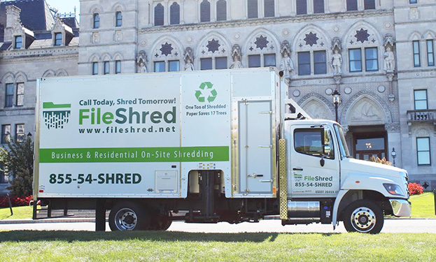 A FileShred mobile shredding truck parked outside of a building