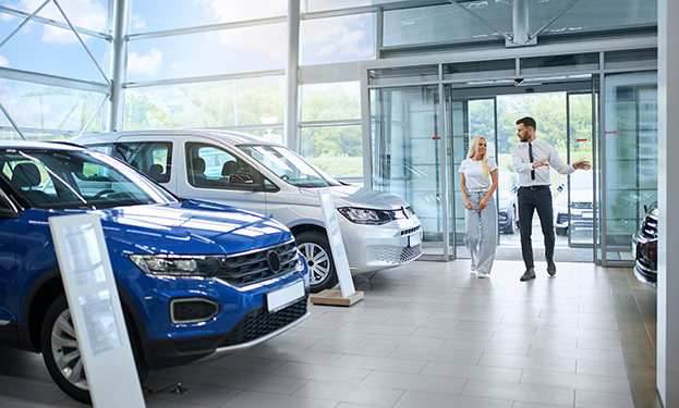 A car dealership sales person walking with a customer through a showroom