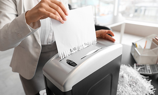 A person putting a document through a home office shredder
