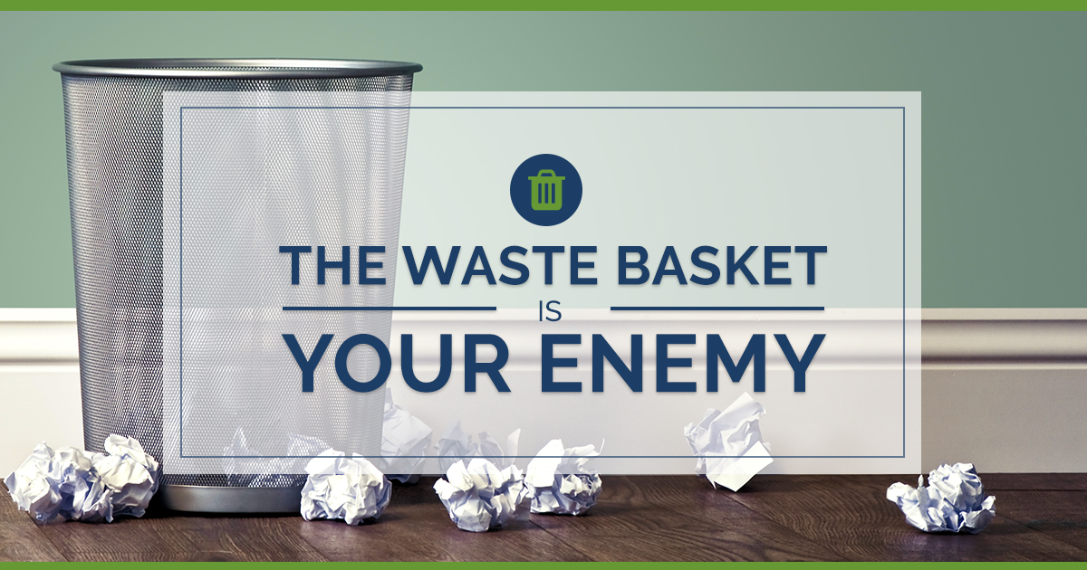 The waste basket is your enemy crumbled pieces of paper next to an empty metal trash can