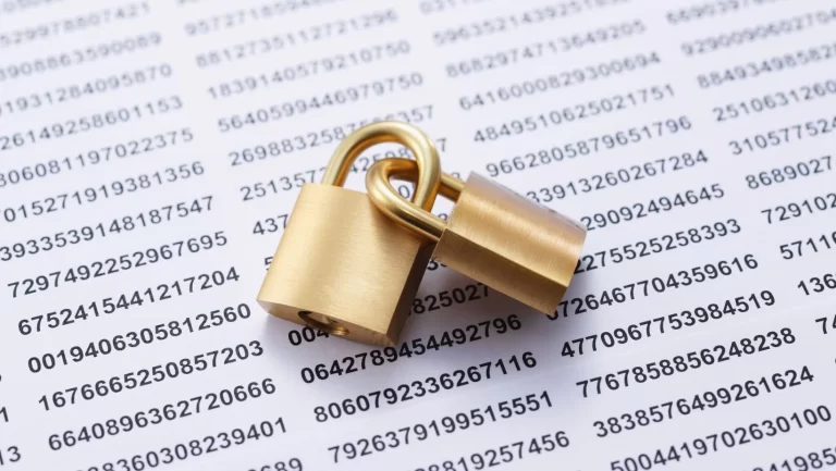 Two gold locks linked together sitting on top of paper with a series of numbers on it.