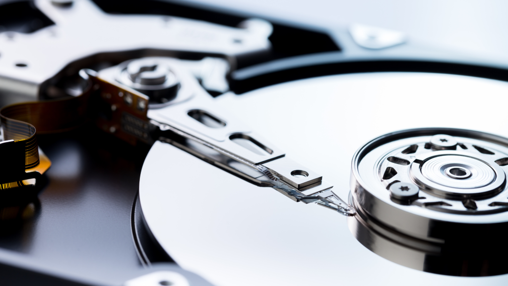 Close-up of an open hard disk drive showing shiny circular platters and a precision read-write arm, highlighting intricate details and metallic textures.